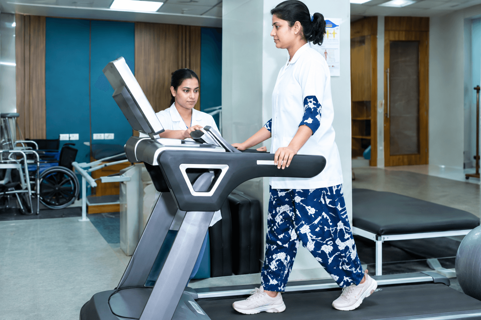 A patient walking on a treadmill supervised by a physiotherapist